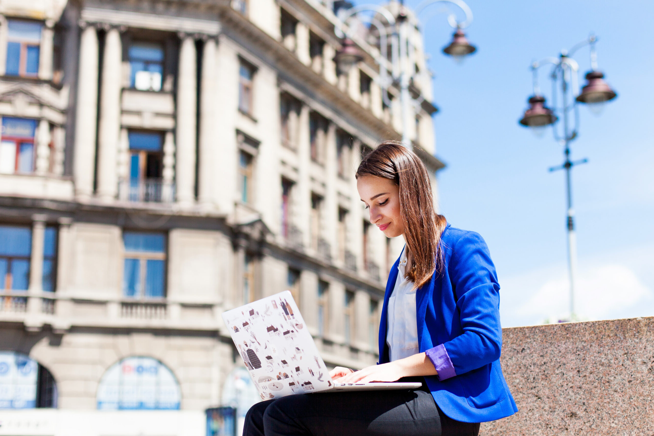 Woman sits on the street and works with a laptop